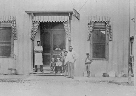 A Family Standing and Sitting Infront of a House